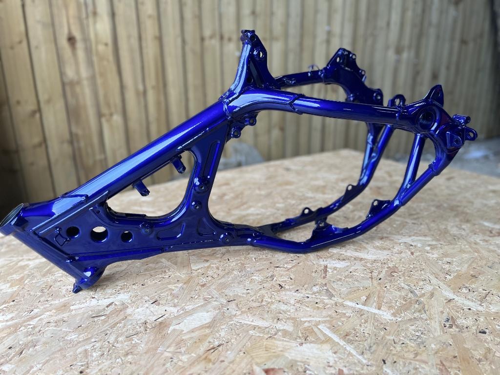 Gloss blue powder-coated motorcycle frame on a workshop surface